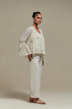 Off-white cotton Chanderi short top with blue & beige block print appliqué, floral embroidery, and beadwork. Paired with straight pants featuring side appliqué and sequin highlights. Elegant, detailed, and handcrafted.