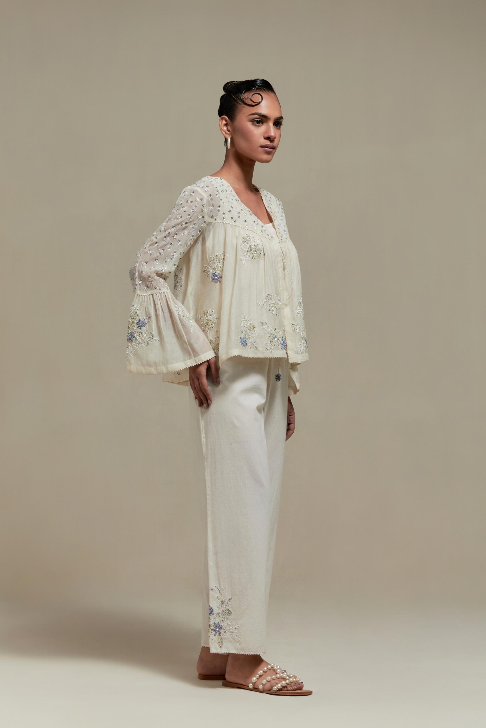 Off-white cotton Chanderi short top with blue & beige block print appliqué, floral embroidery, and beadwork. Paired with straight pants featuring side appliqué and sequin highlights. Elegant, detailed, and handcrafted.