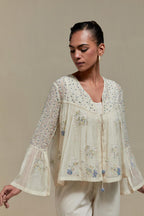 Off-white cotton Chanderi short top with blue & beige block print appliqué, floral embroidery, and beadwork. Paired with straight pants featuring side appliqué and sequin highlights. Elegant, detailed, and handcrafted.