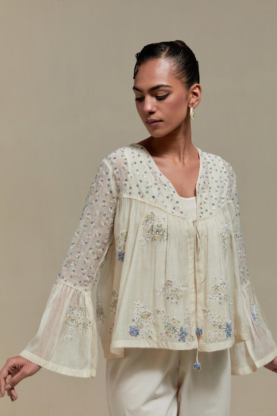 Off-white cotton Chanderi short top with blue & beige block print appliqué, floral embroidery, and beadwork. Paired with straight pants featuring side appliqué and sequin highlights. Elegant, detailed, and handcrafted.