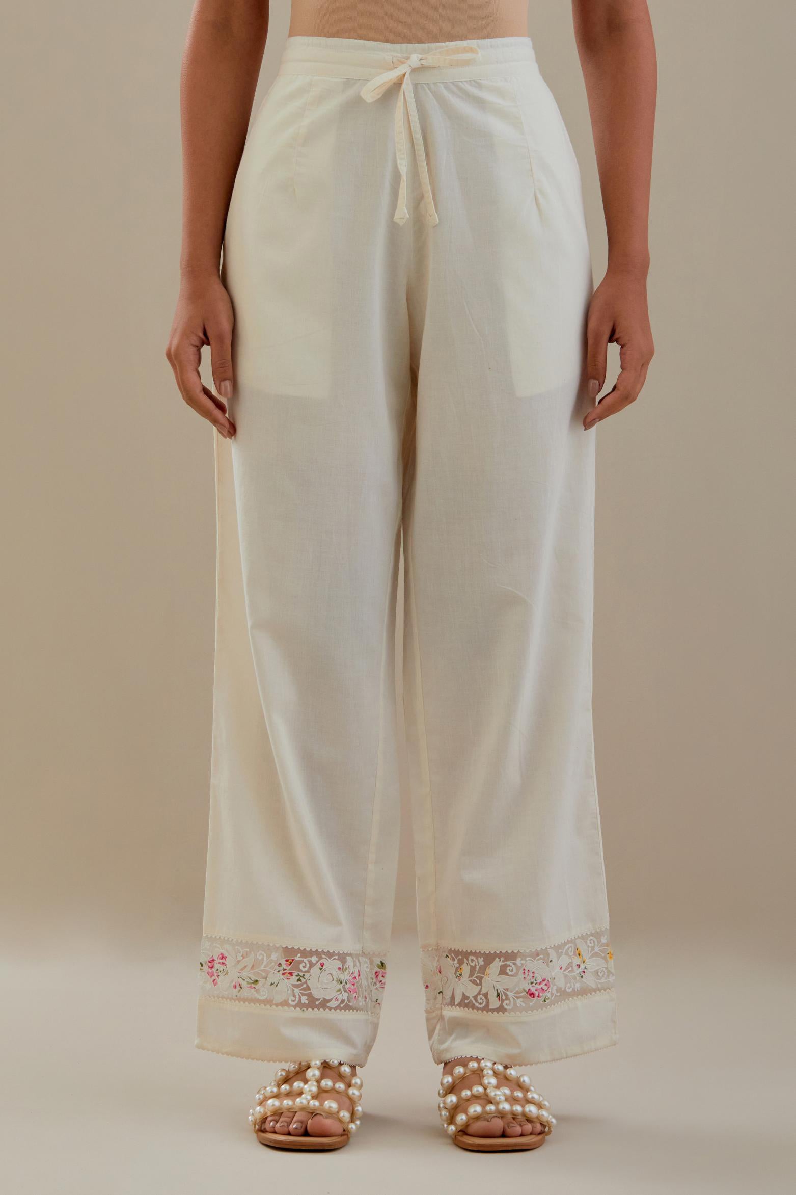 Off white straight pants detailed with applique work at bottom.