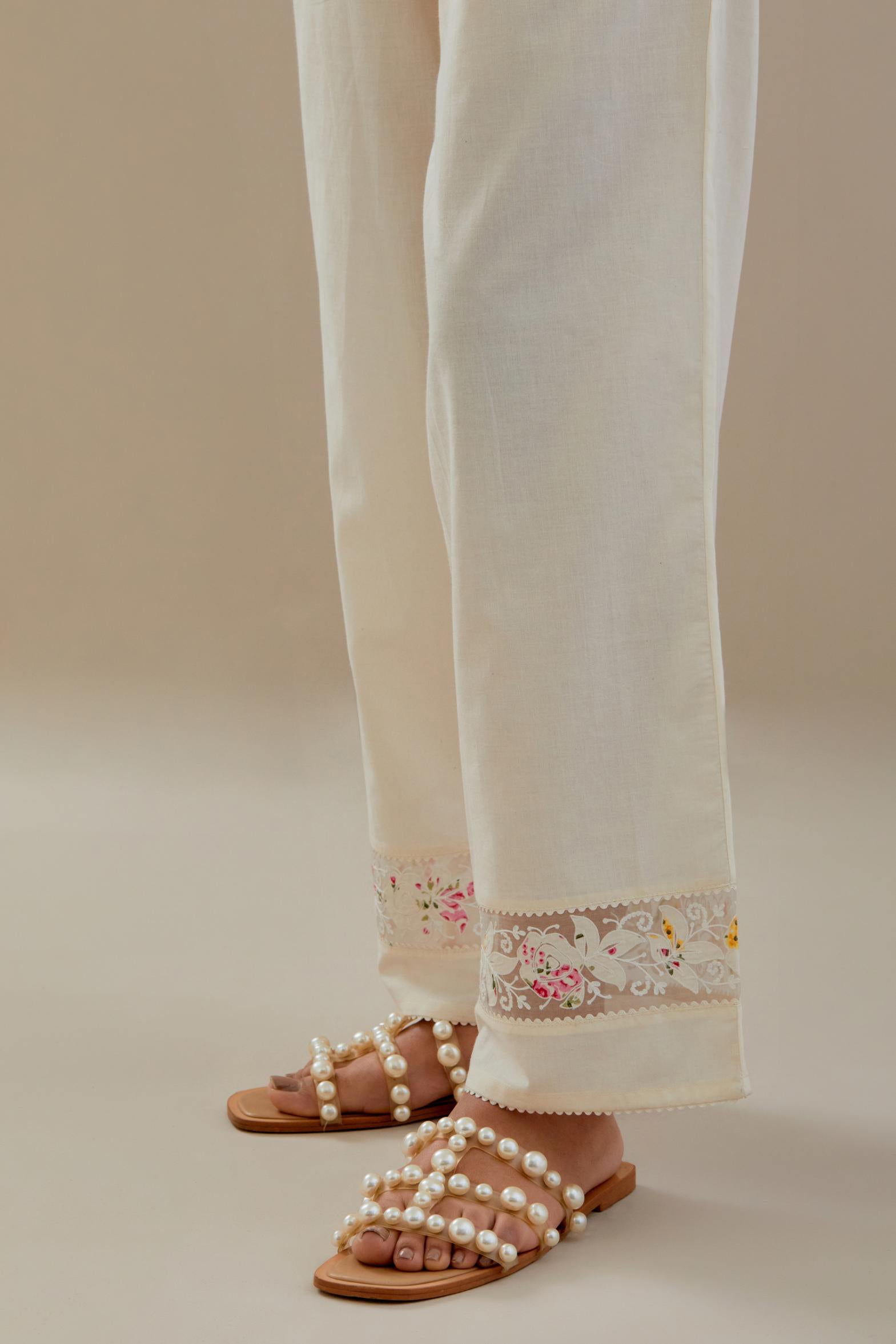 Off white straight pants detailed with applique work at bottom.