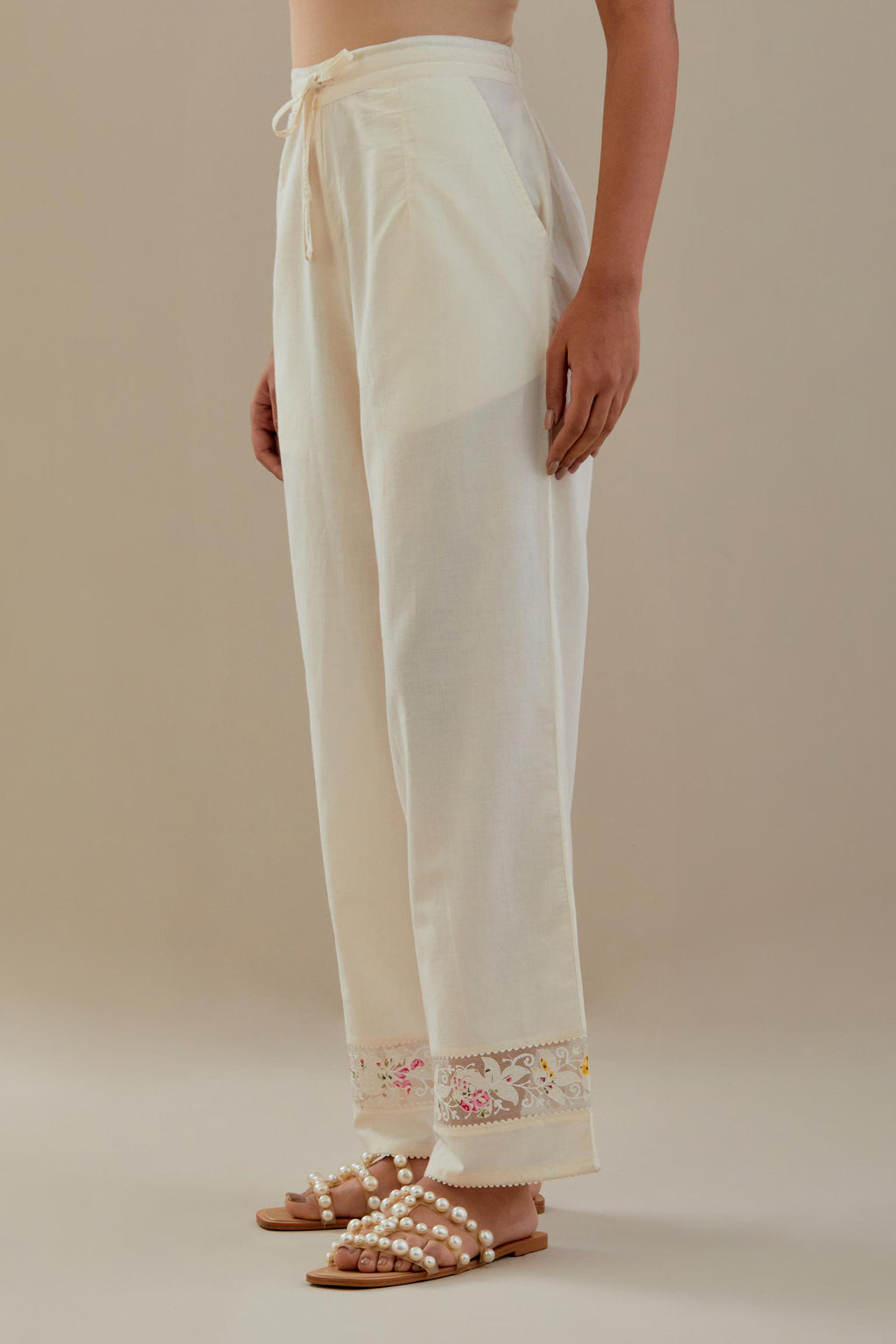 Off white straight pants detailed with applique work at bottom.