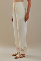 Off white straight pants detailed with applique work at bottom.