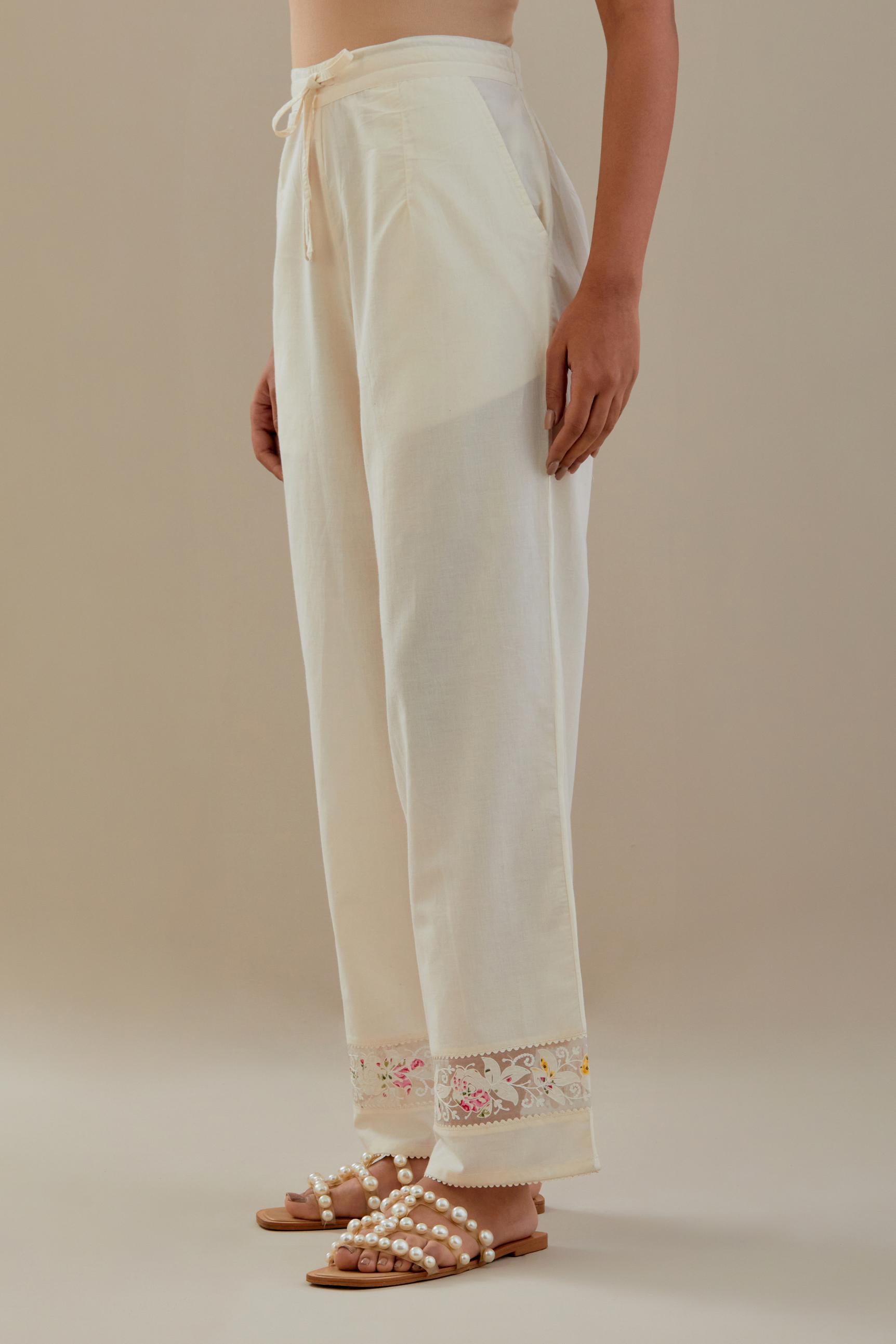 Off white straight pants detailed with applique work at bottom.