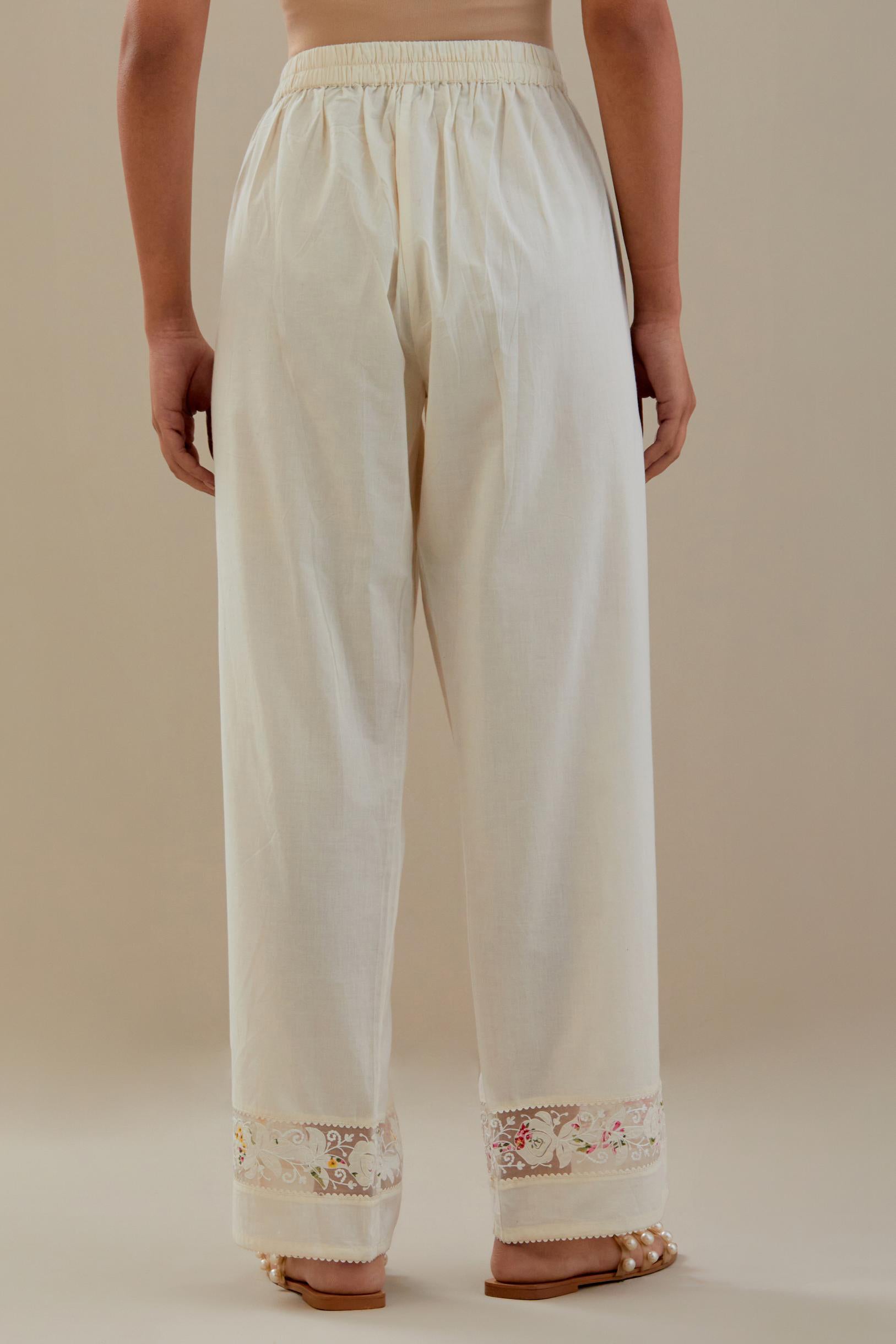 Off white straight pants detailed with applique work at bottom.