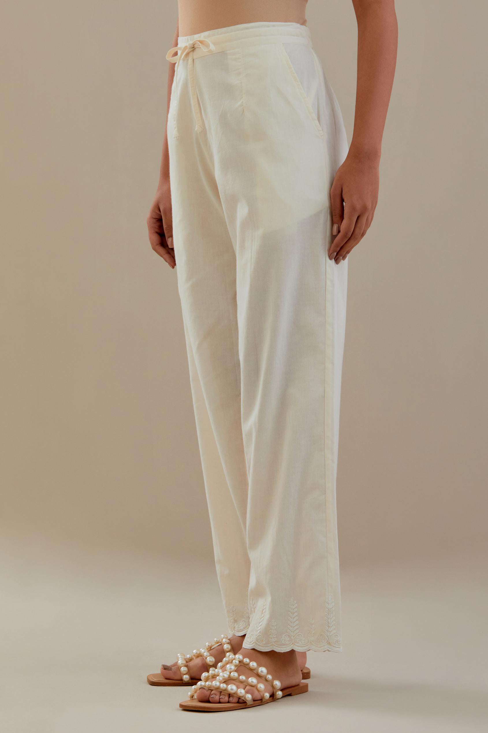 Off white cotton straight pants with off white dori embroidery at hem, highlighted with sequins work. 