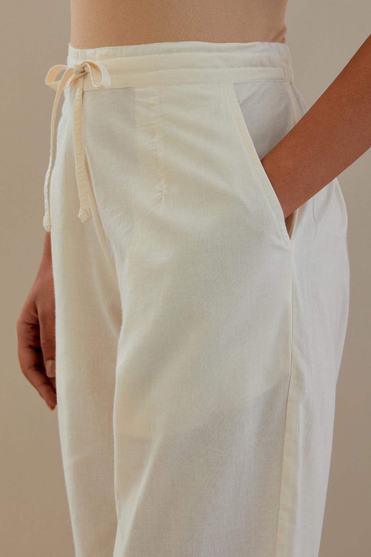 Off white cotton straight pants with off white dori embroidery at hem, highlighted with sequins work. 