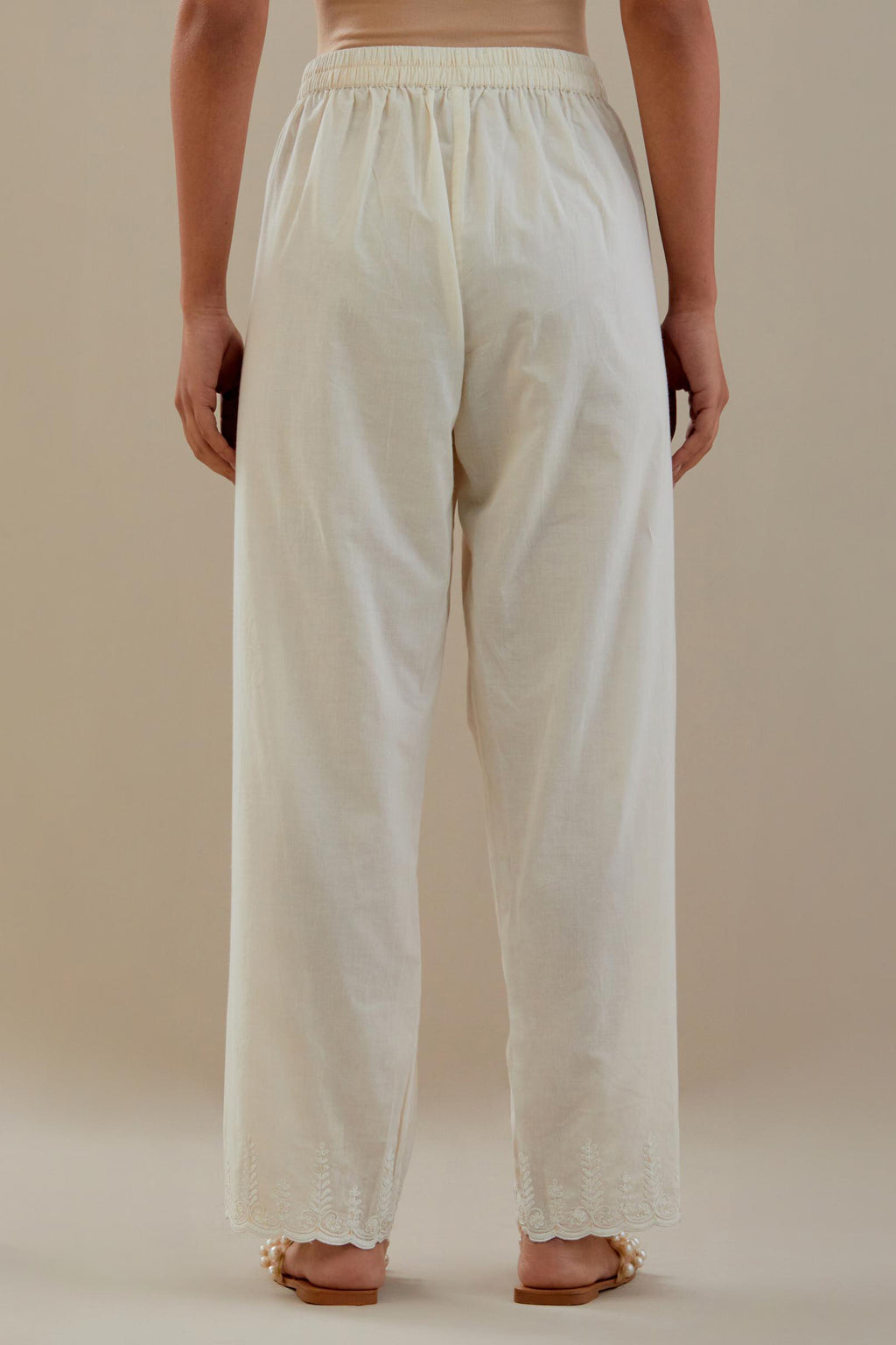 Off white cotton straight pants with off white dori embroidery at hem, highlighted with sequins work. 