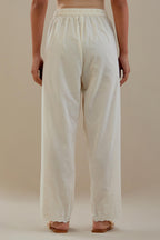Off white cotton straight pants with off white dori embroidery at hem, highlighted with sequins work. 