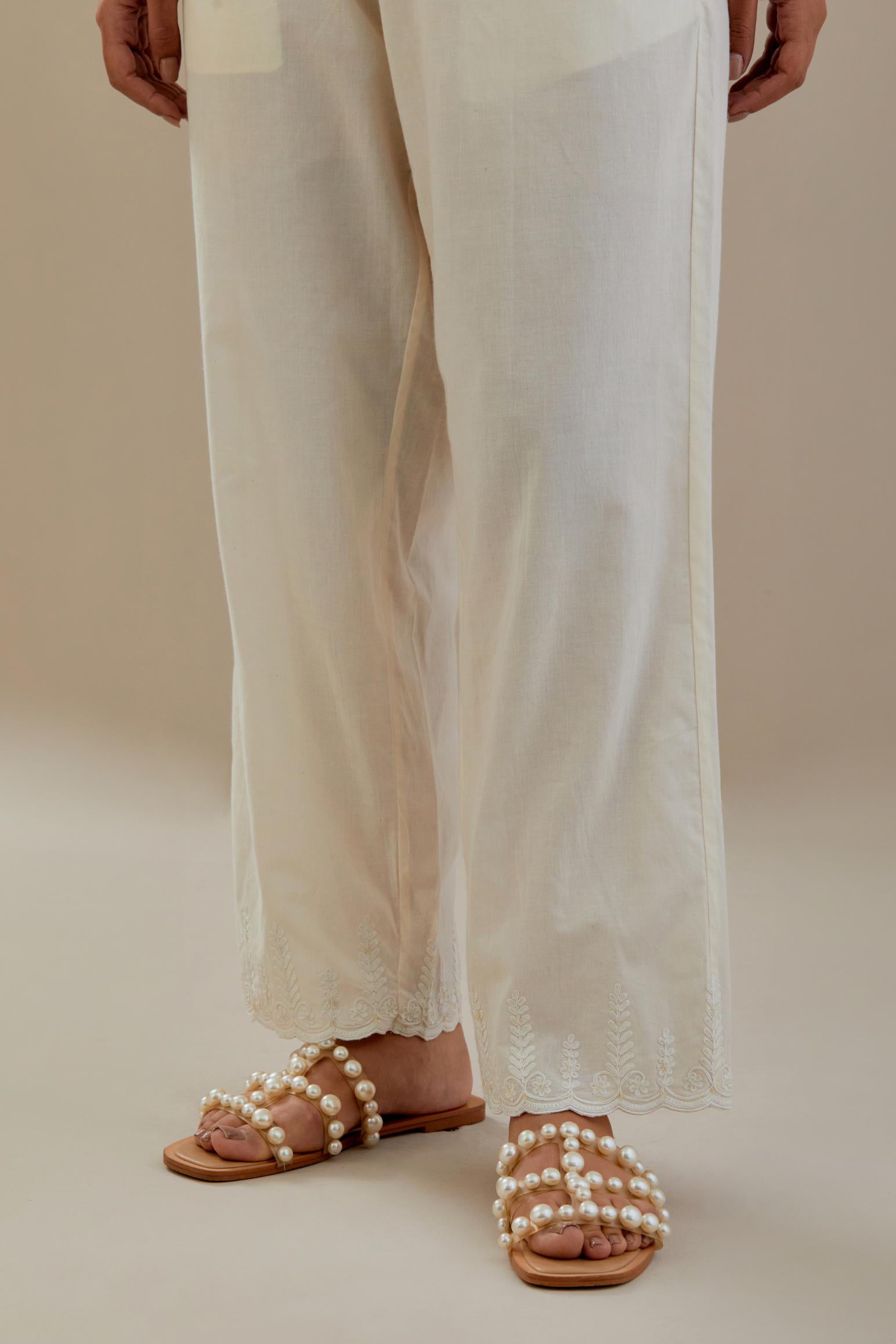 Off white cotton straight pants with off white dori embroidery at hem, highlighted with sequins work. 