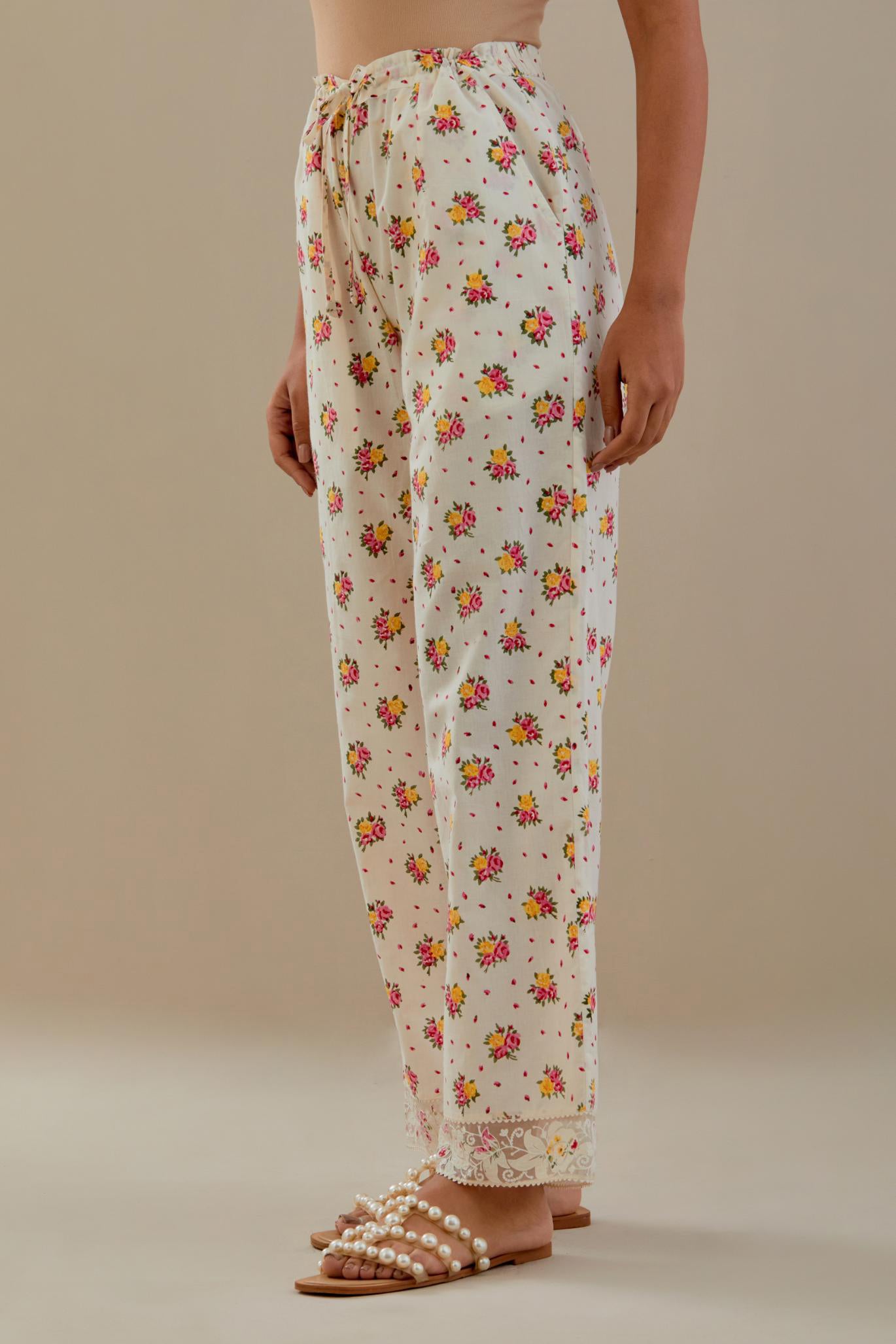 Off white cotton straight pants with all-over small multi colored hand block print, detailed with applique work at bottom.