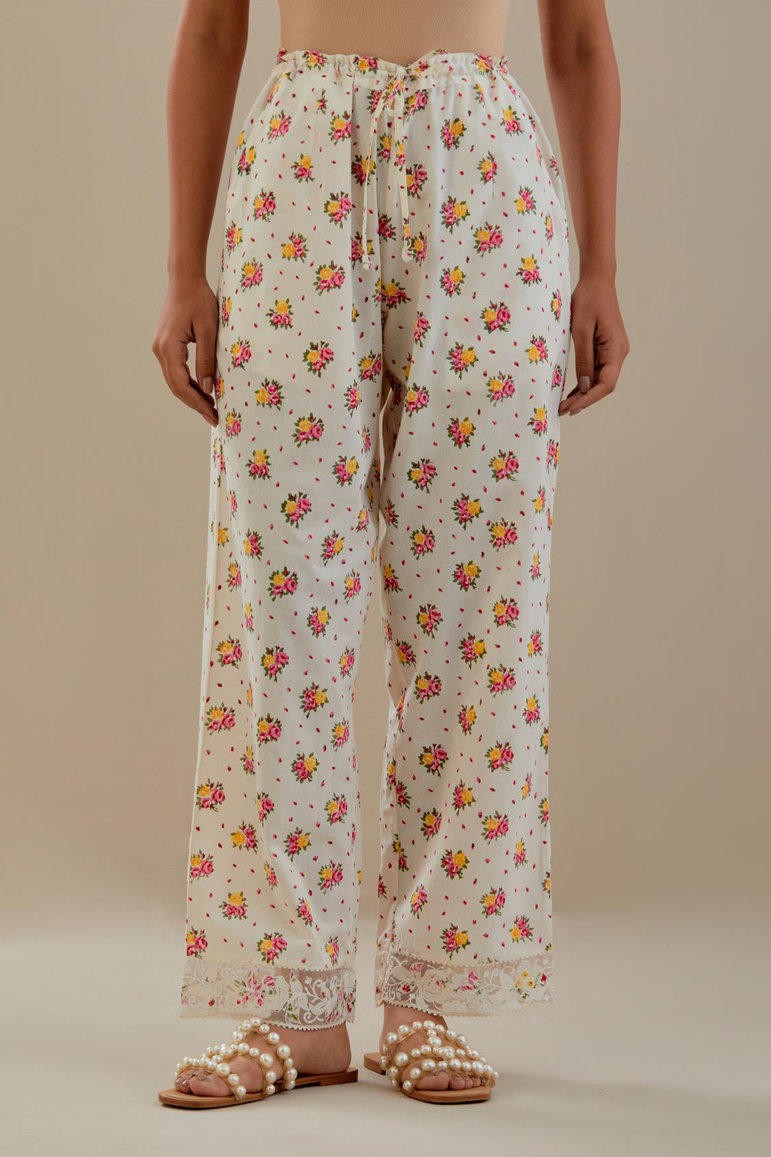 Off white cotton straight pants with all-over small multi colored hand block print, detailed with applique work at bottom.