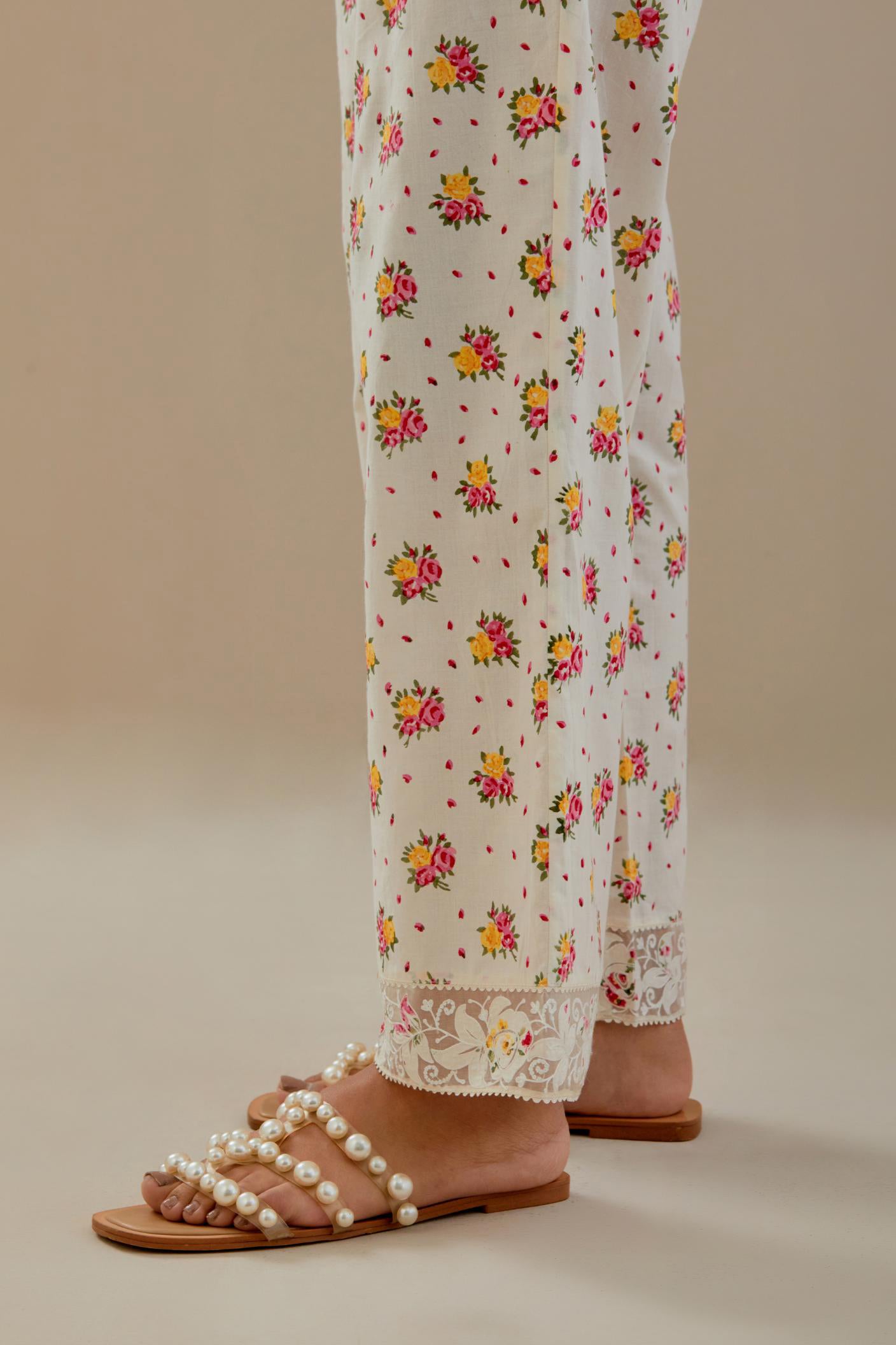 Off white cotton straight pants with all-over small multi colored hand block print, detailed with applique work at bottom.