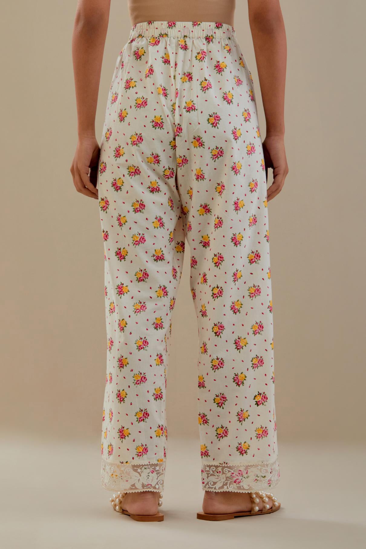 Off white cotton straight pants with all-over small multi colored hand block print, detailed with applique work at bottom.