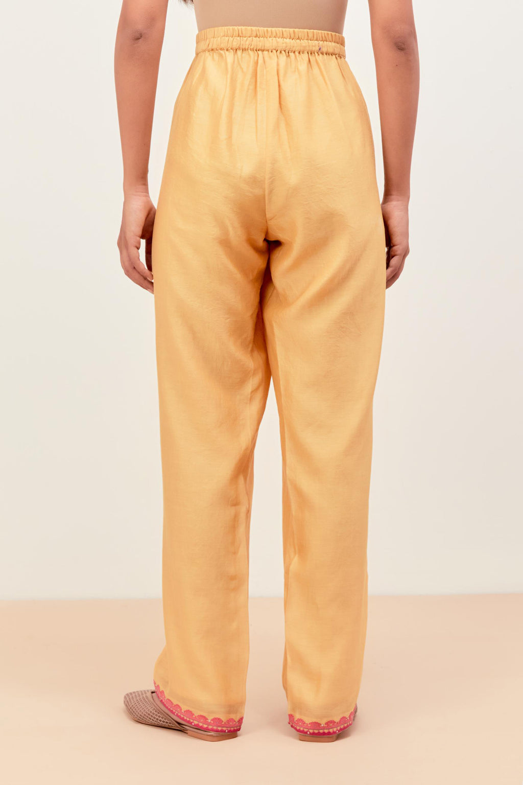 Yellow silk chanderi straight pants detailed with multi colored applique, highlighted with sequins work at bottom hem.