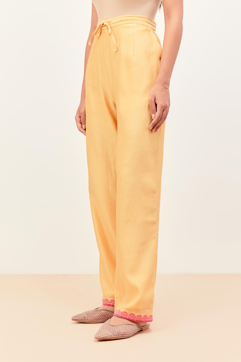 Yellow silk chanderi straight pants detailed with multi colored applique, highlighted with sequins work at bottom hem.