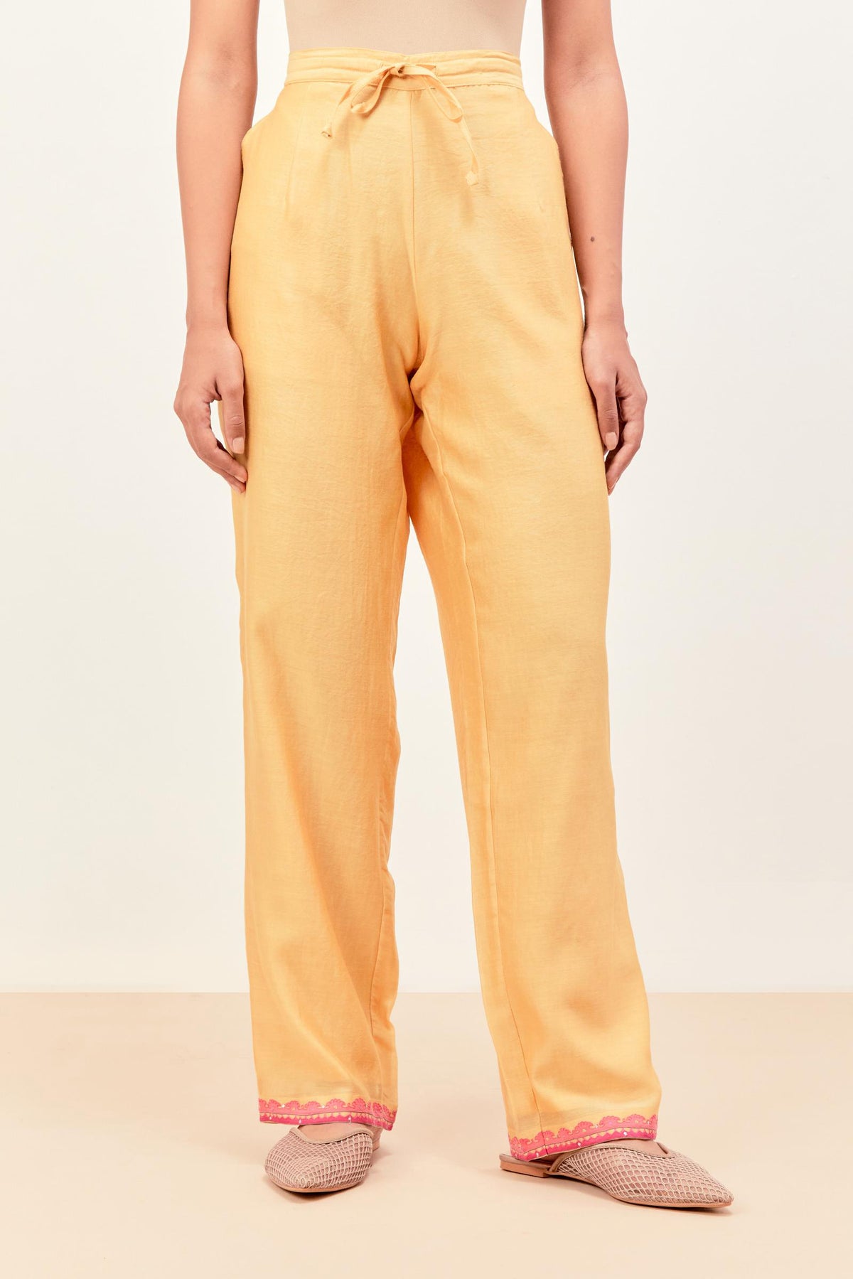 Yellow silk chanderi straight pants detailed with multi colored applique, highlighted with sequins work at bottom hem.