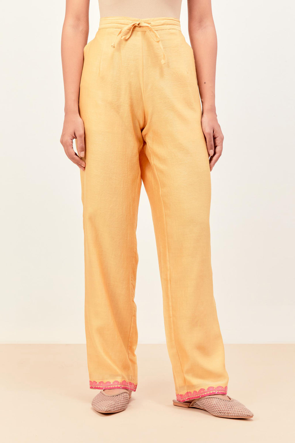 Yellow silk chanderi straight pants detailed with multi colored applique, highlighted with sequins work at bottom hem.