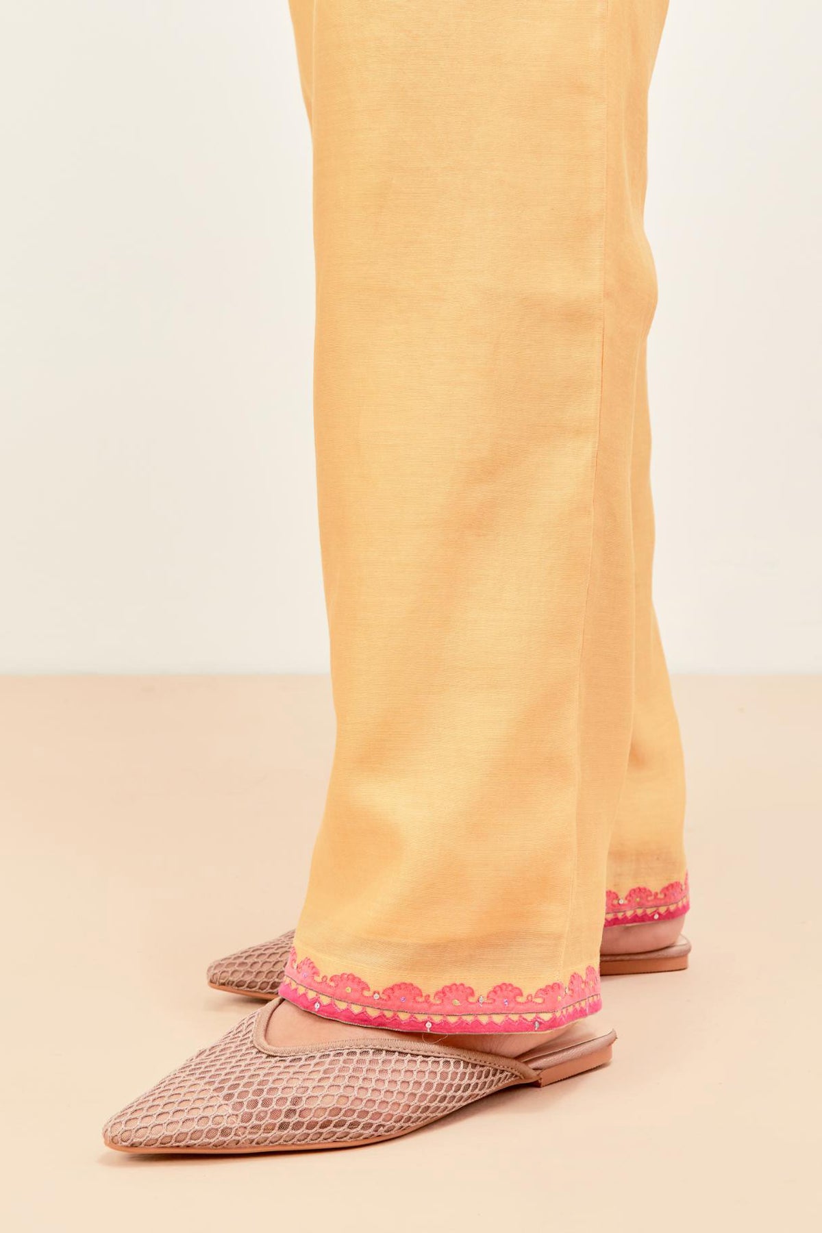 Yellow silk chanderi straight pants detailed with multi colored applique, highlighted with sequins work at bottom hem.