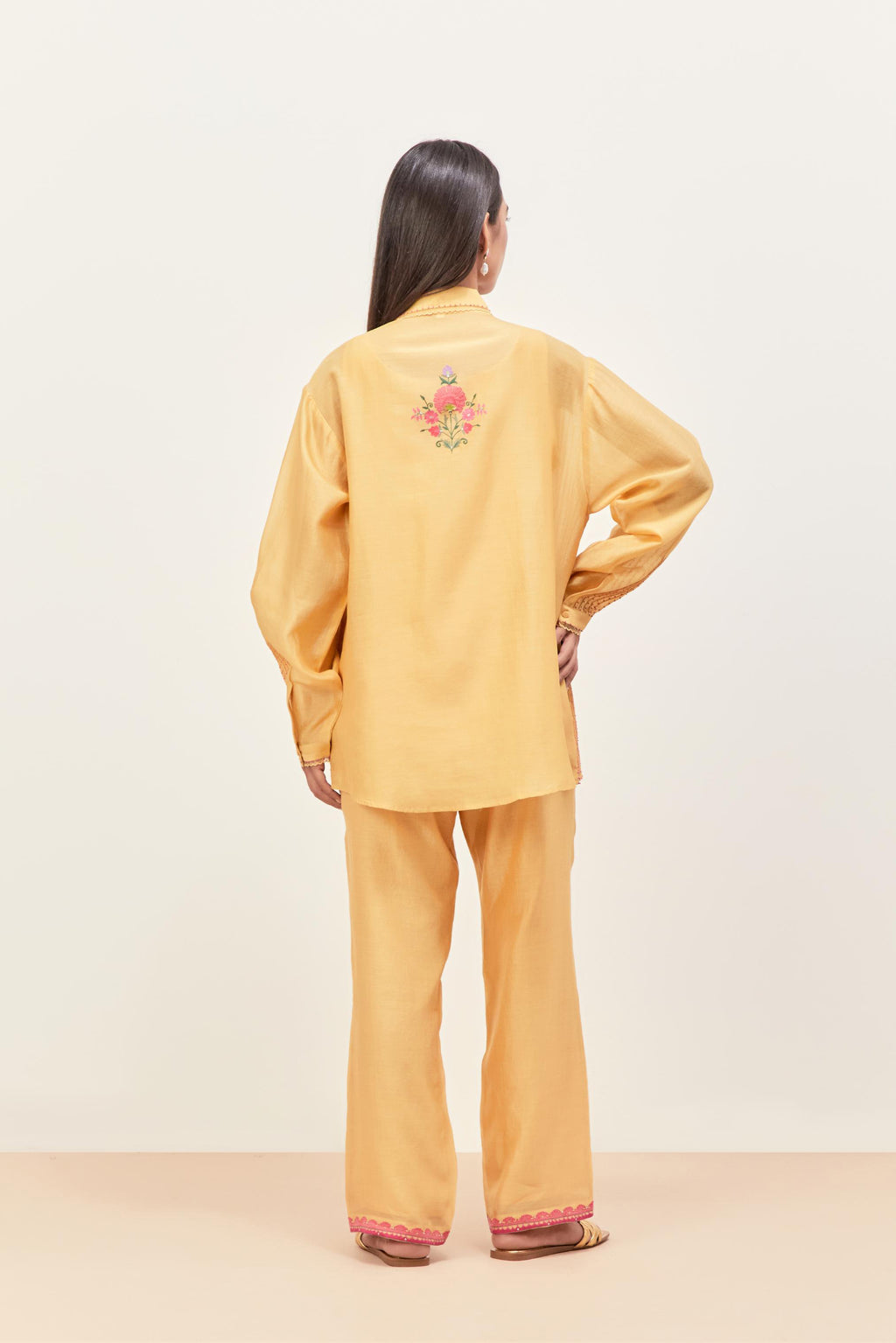 Yellow silk chanderi shirt with all-over pin tucks, highlighted with contrast beads in the front, paired with yellow silk chanderi straight pants detailed with multi colored applique, highlighted with sequins work at bottom hem.