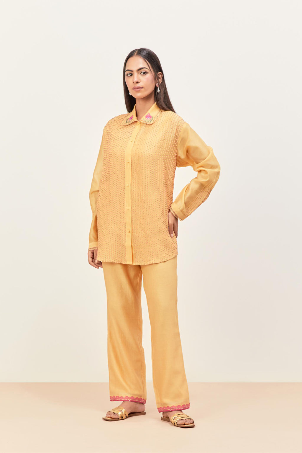 Yellow silk chanderi shirt with all-over pin tucks, highlighted with contrast beads in the front, paired with yellow silk chanderi straight pants detailed with multi colored applique, highlighted with sequins work at bottom hem.