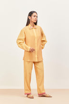 Yellow silk chanderi shirt with all-over pin tucks, highlighted with contrast beads in the front, paired with yellow silk chanderi straight pants detailed with multi colored applique, highlighted with sequins work at bottom hem.