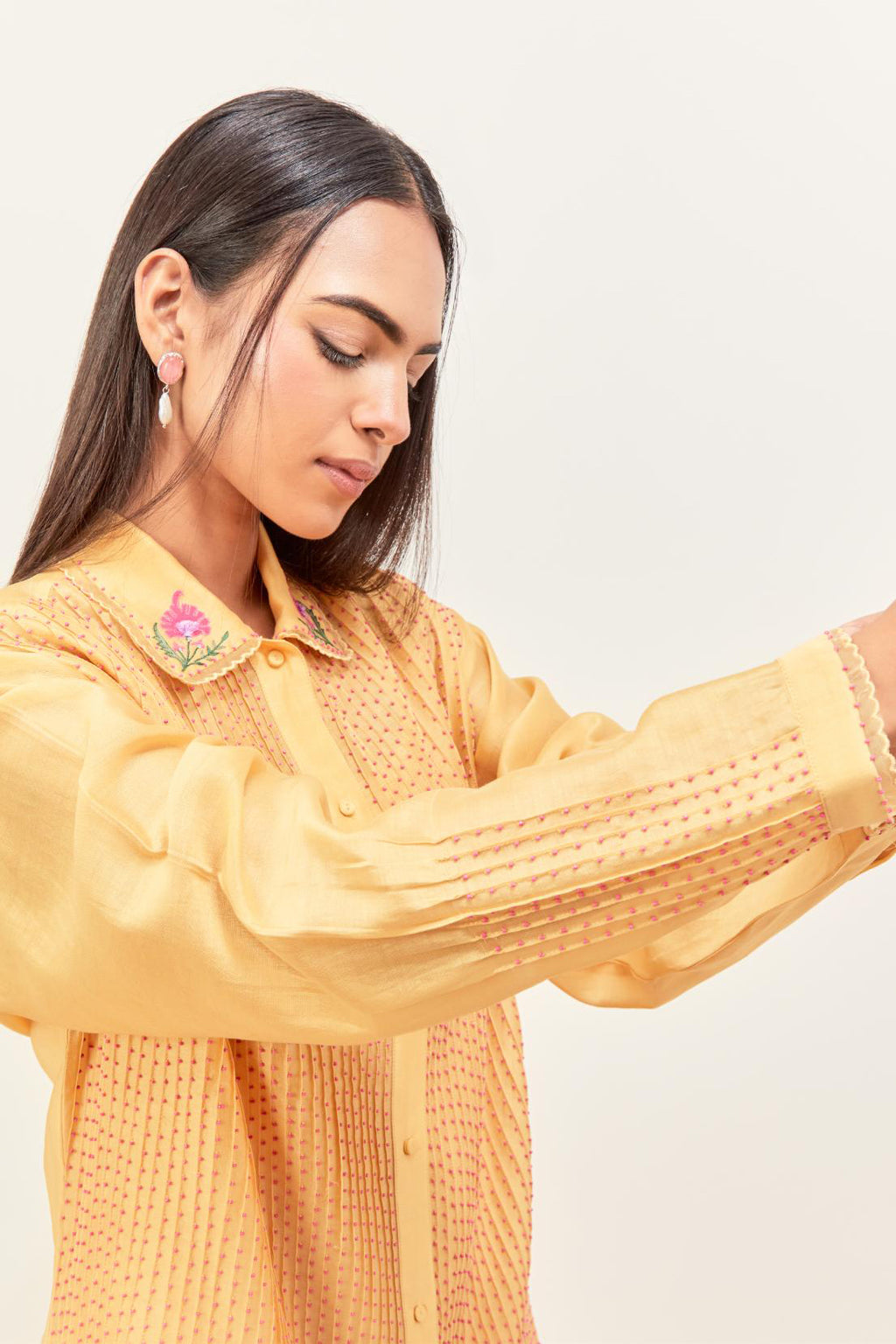 Yellow silk chanderi shirt with all-over pin tucks, highlighted with contrast beads in the front, paired with yellow silk chanderi straight pants detailed with multi colored applique, highlighted with sequins work at bottom hem.