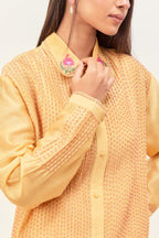 Yellow silk chanderi shirt with all-over pin tucks, highlighted with contrast beads in the front, paired with yellow silk chanderi straight pants detailed with multi colored applique, highlighted with sequins work at bottom hem.