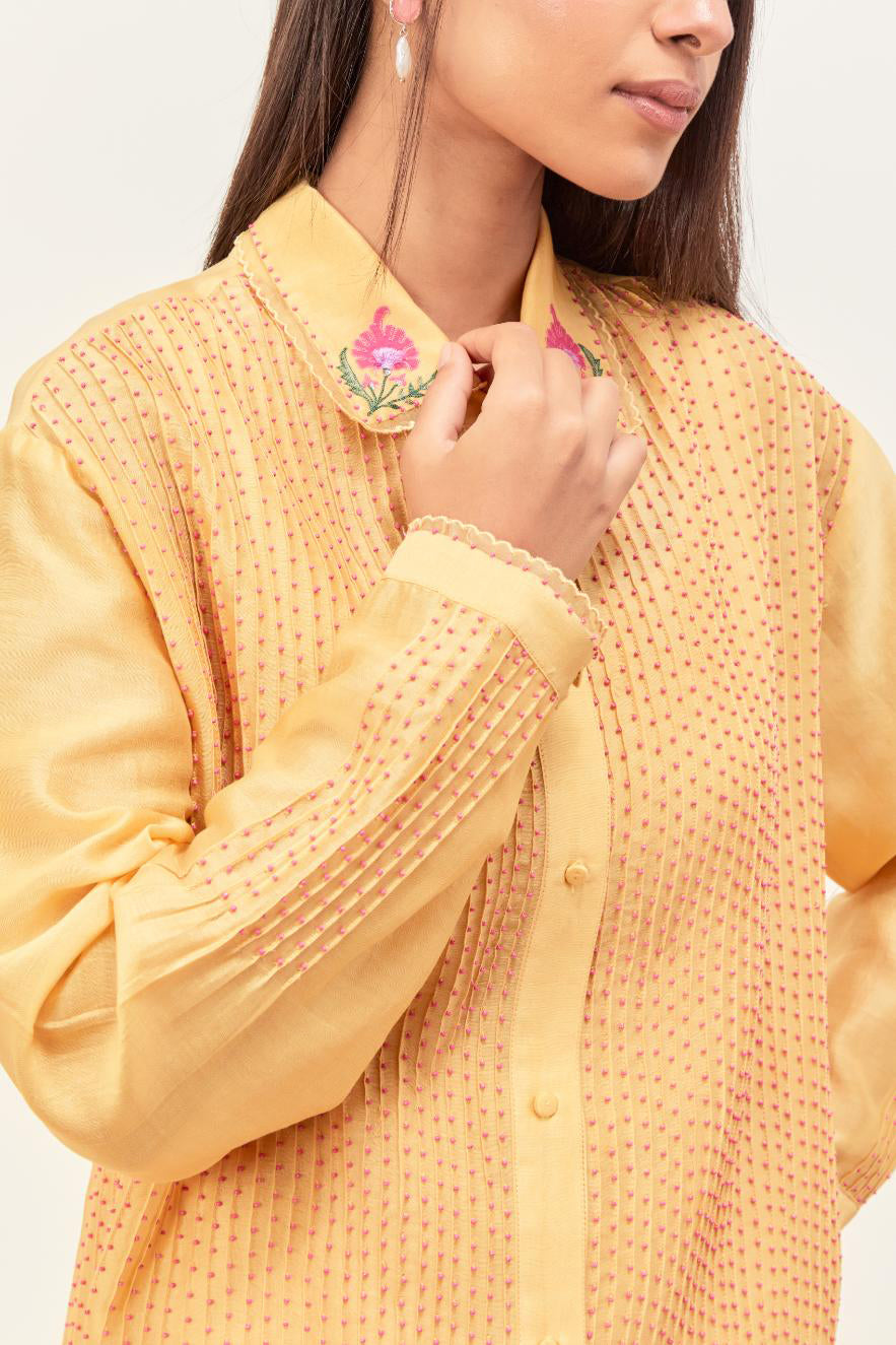 Yellow silk chanderi shirt with all-over pin tucks, highlighted with contrast beads in the front, paired with yellow silk chanderi straight pants detailed with multi colored applique, highlighted with sequins work at bottom hem.