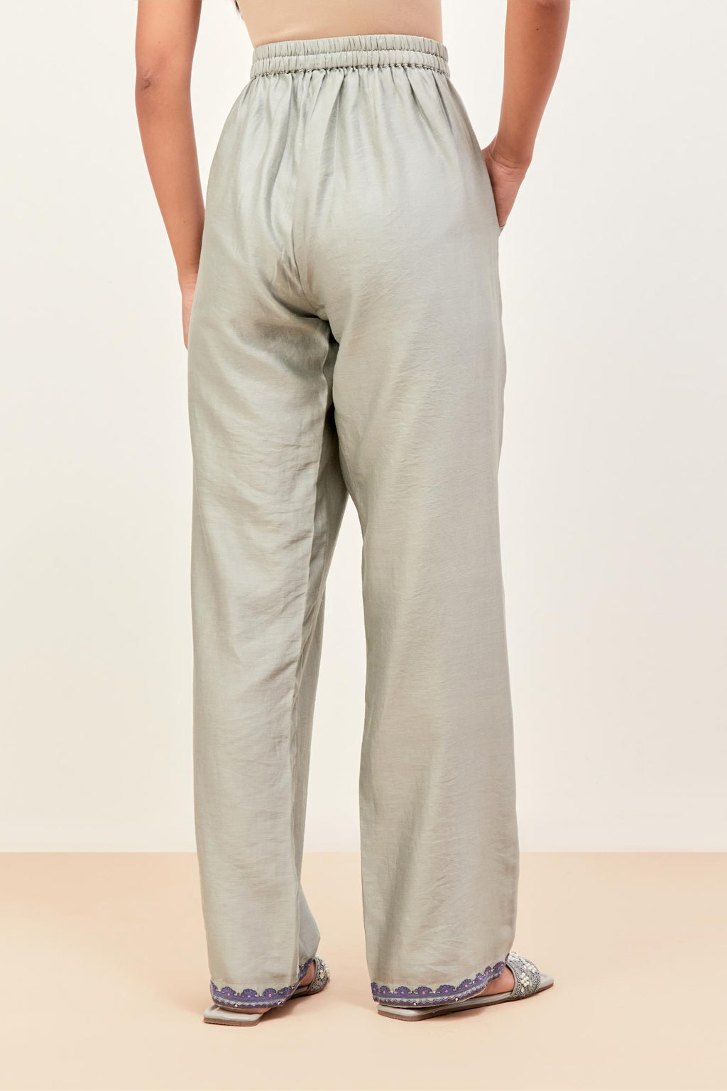 Bluish grey silk chanderi straight pants detailed with multi colored applique, highlighted with sequins work at bottom hem.