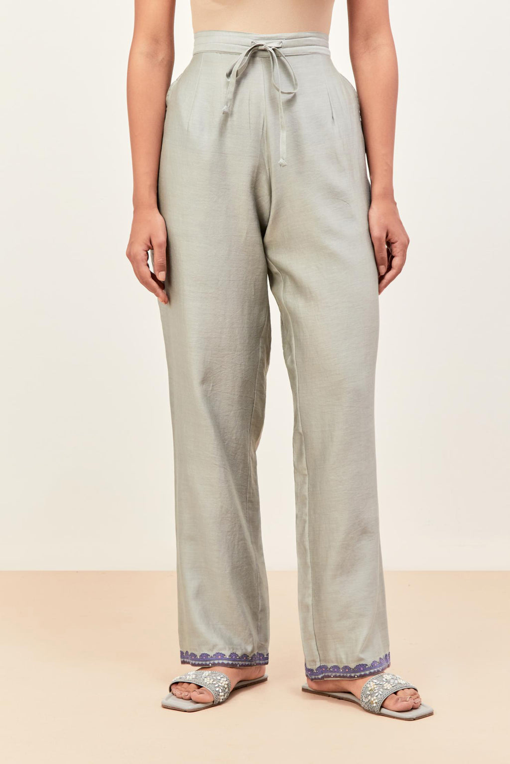 Bluish grey silk chanderi straight pants detailed with multi colored applique, highlighted with sequins work at bottom hem.