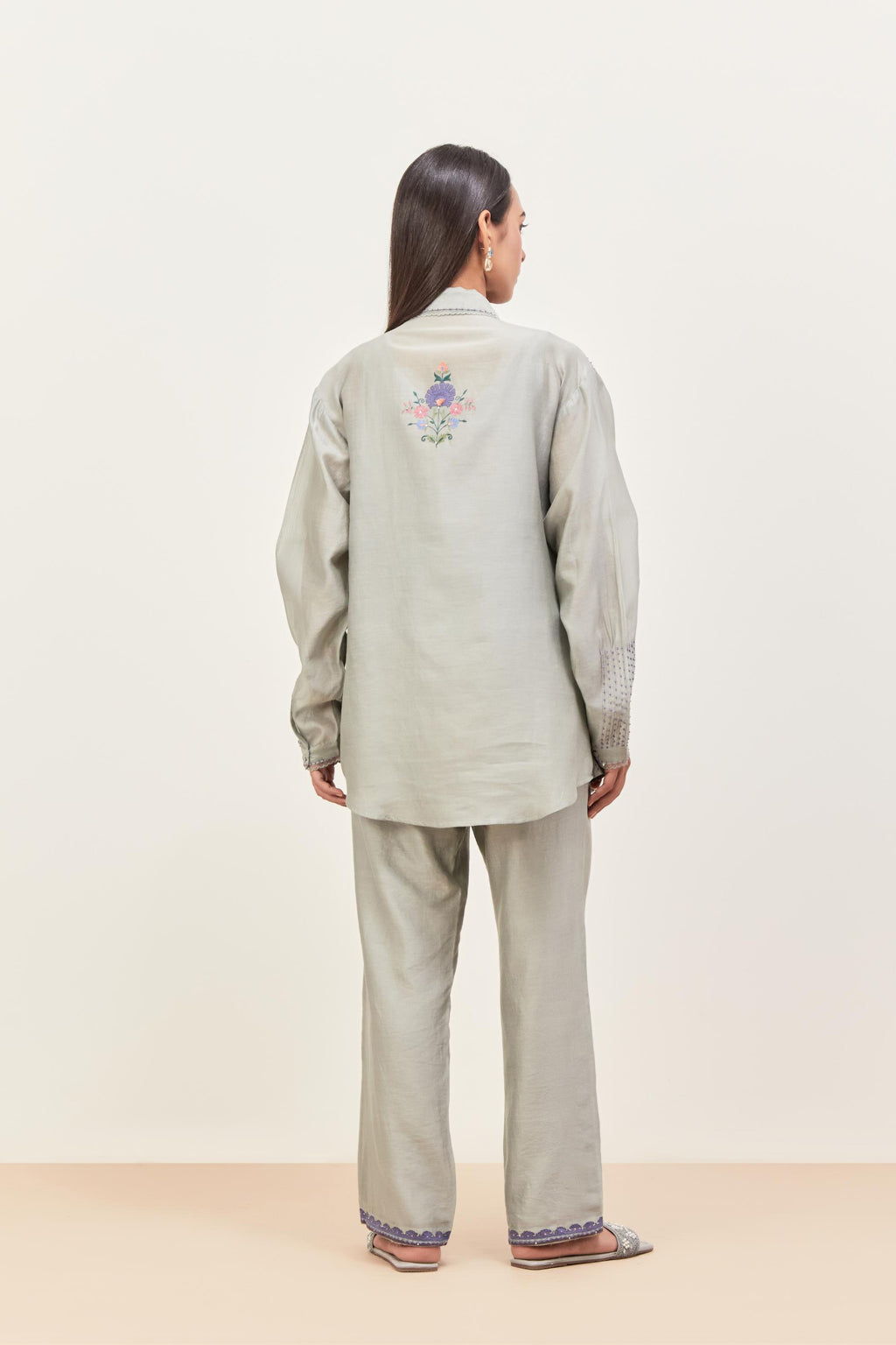 Bluish Grey silk chanderi shirt with all-over pin tucks, highlighted with contrast beads in the front, paired with Bluish Grey silk chanderi straight pants detailed with multi colored applique, highlighted with sequins work at bottom hem.