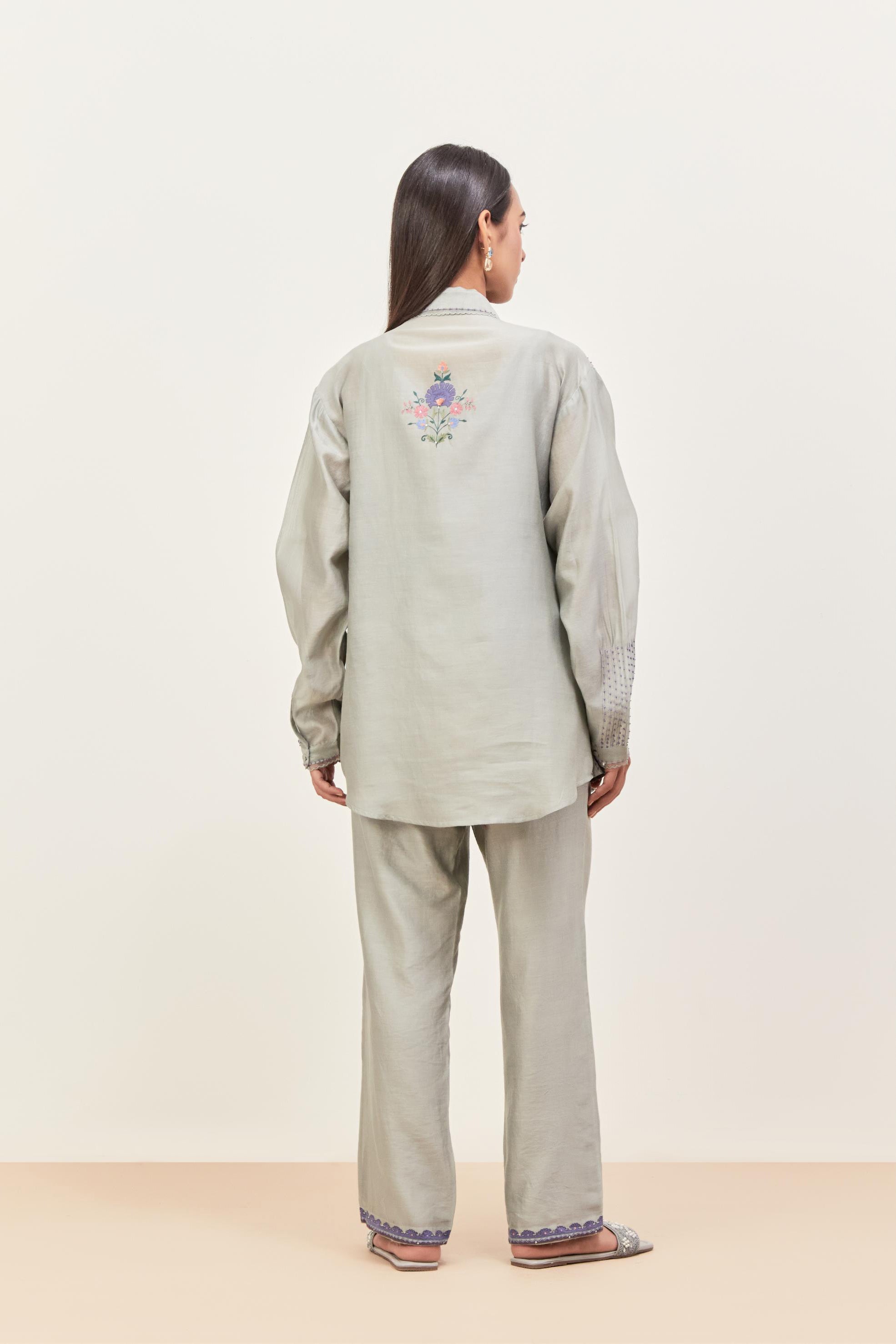 Bluish Grey silk chanderi shirt with all-over pin tucks, highlighted with contrast beads in the front, paired with Bluish Grey silk chanderi straight pants detailed with multi colored applique, highlighted with sequins work at bottom hem.