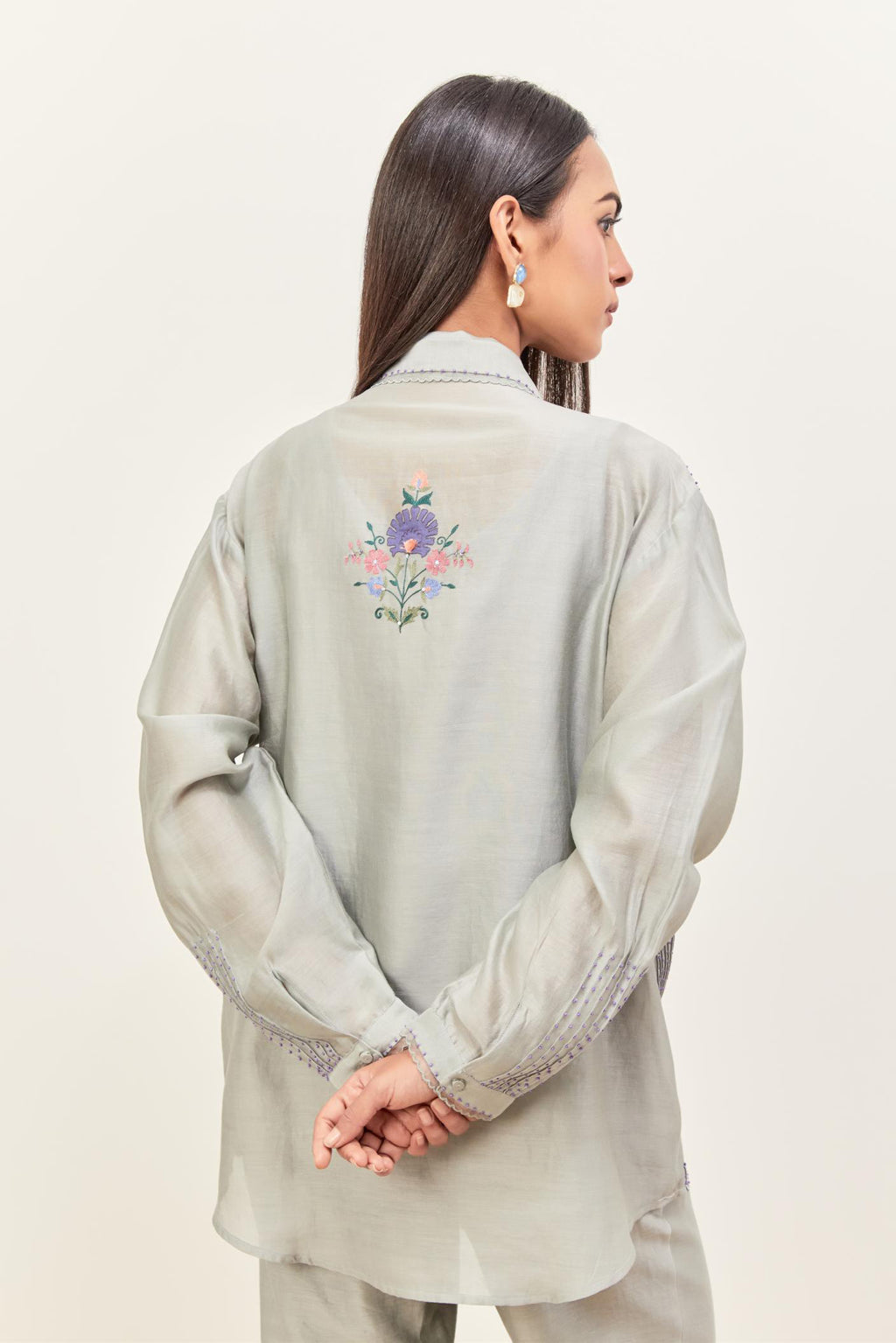 Bluish Grey silk chanderi shirt with all-over pin tucks, highlighted with contrast beads in the front, paired with Bluish Grey silk chanderi straight pants detailed with multi colored applique, highlighted with sequins work at bottom hem.