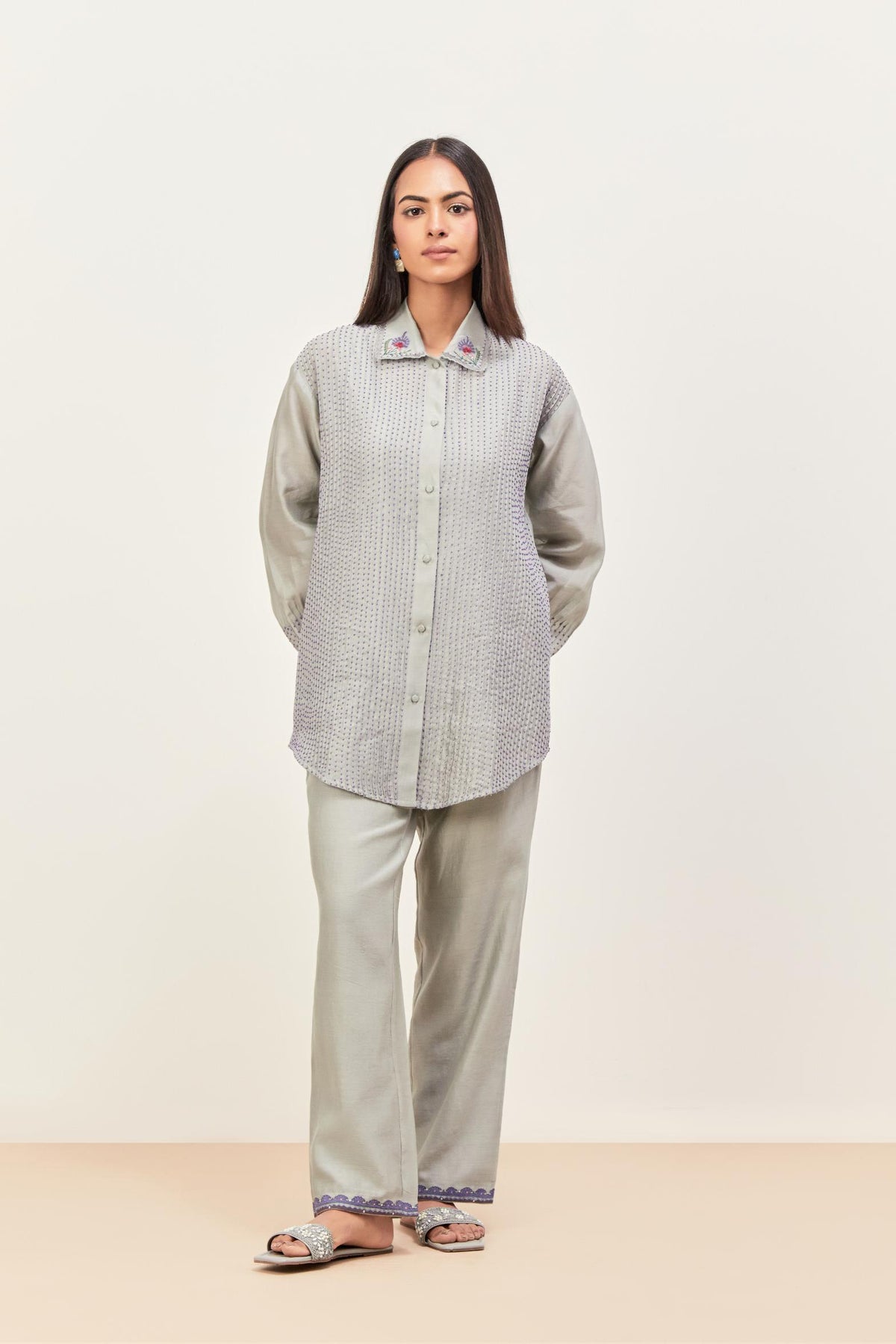 Bluish Grey silk chanderi shirt with all-over pin tucks, highlighted with contrast beads in the front, paired with Bluish Grey silk chanderi straight pants detailed with multi colored applique, highlighted with sequins work at bottom hem.