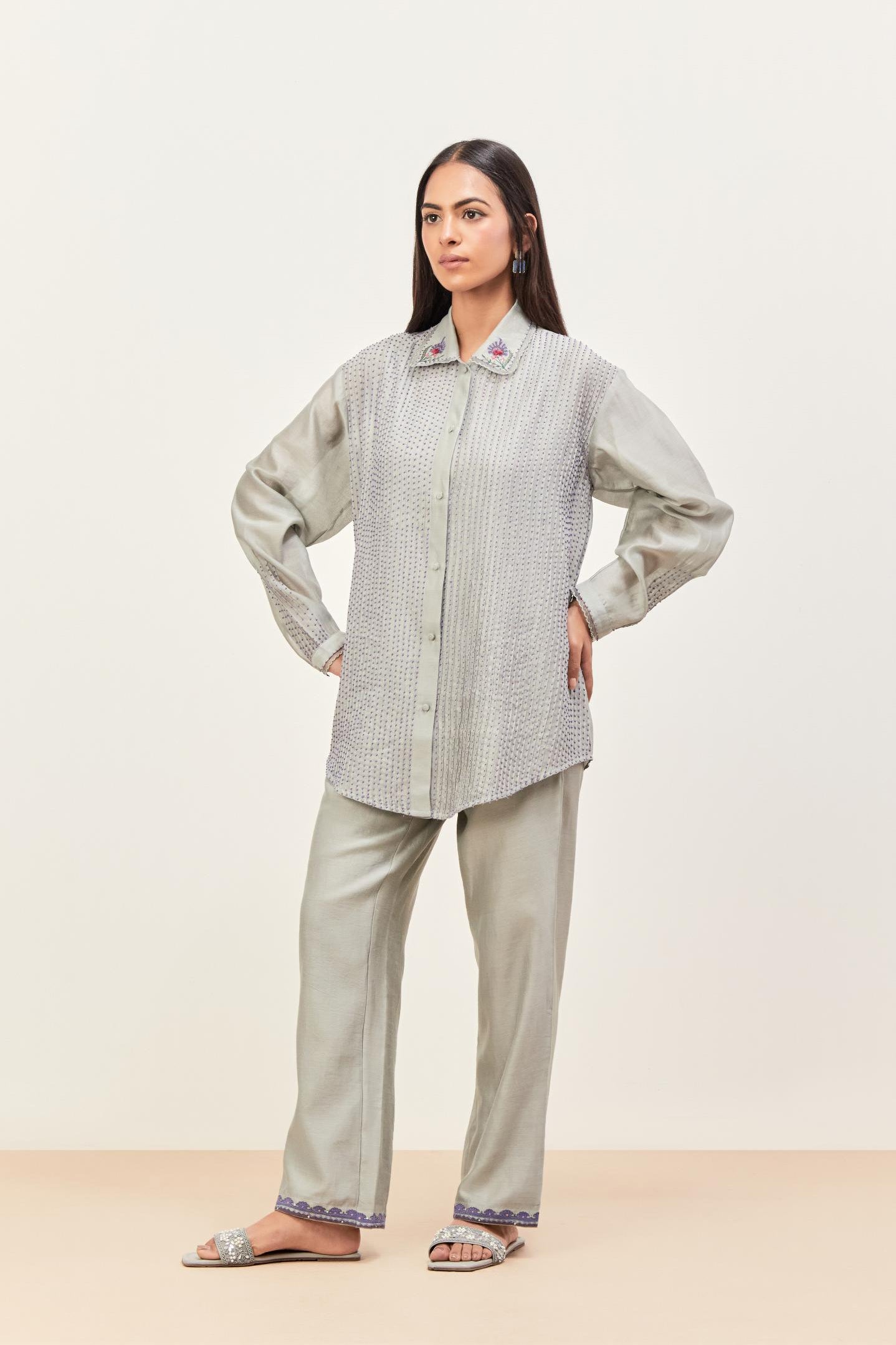 Bluish Grey silk chanderi shirt with all-over pin tucks, highlighted with contrast beads in the front, paired with Bluish Grey silk chanderi straight pants detailed with multi colored applique, highlighted with sequins work at bottom hem.