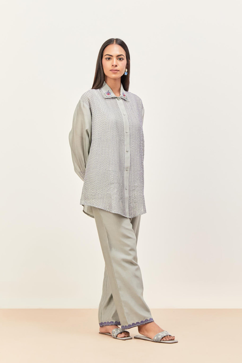 Bluish Grey silk chanderi shirt with all-over pin tucks, highlighted with contrast beads in the front, paired with Bluish Grey silk chanderi straight pants detailed with multi colored applique, highlighted with sequins work at bottom hem.