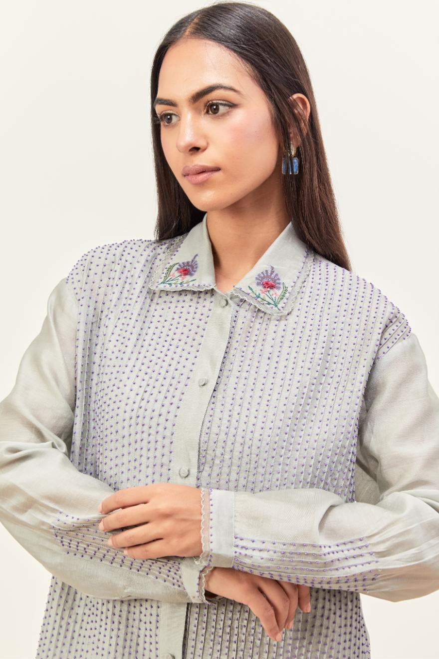 Bluish Grey silk chanderi shirt with all-over pin tucks, highlighted with contrast beads in the front, paired with Bluish Grey silk chanderi straight pants detailed with multi colored applique, highlighted with sequins work at bottom hem.