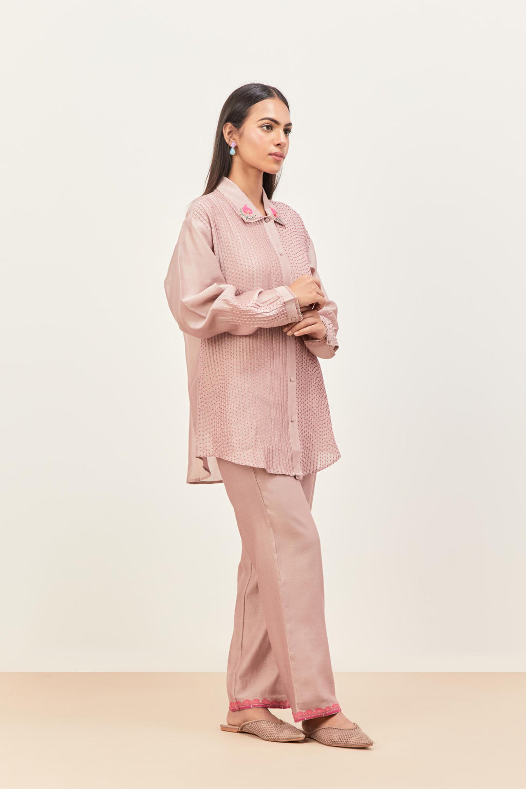 Lilac silk chanderi shirt with all-over pin tucks, highlighted with contrast beads in the front, paired with Lilac silk chanderi straight pants detailed with multi colored applique, highlighted with sequins work at bottom hem.