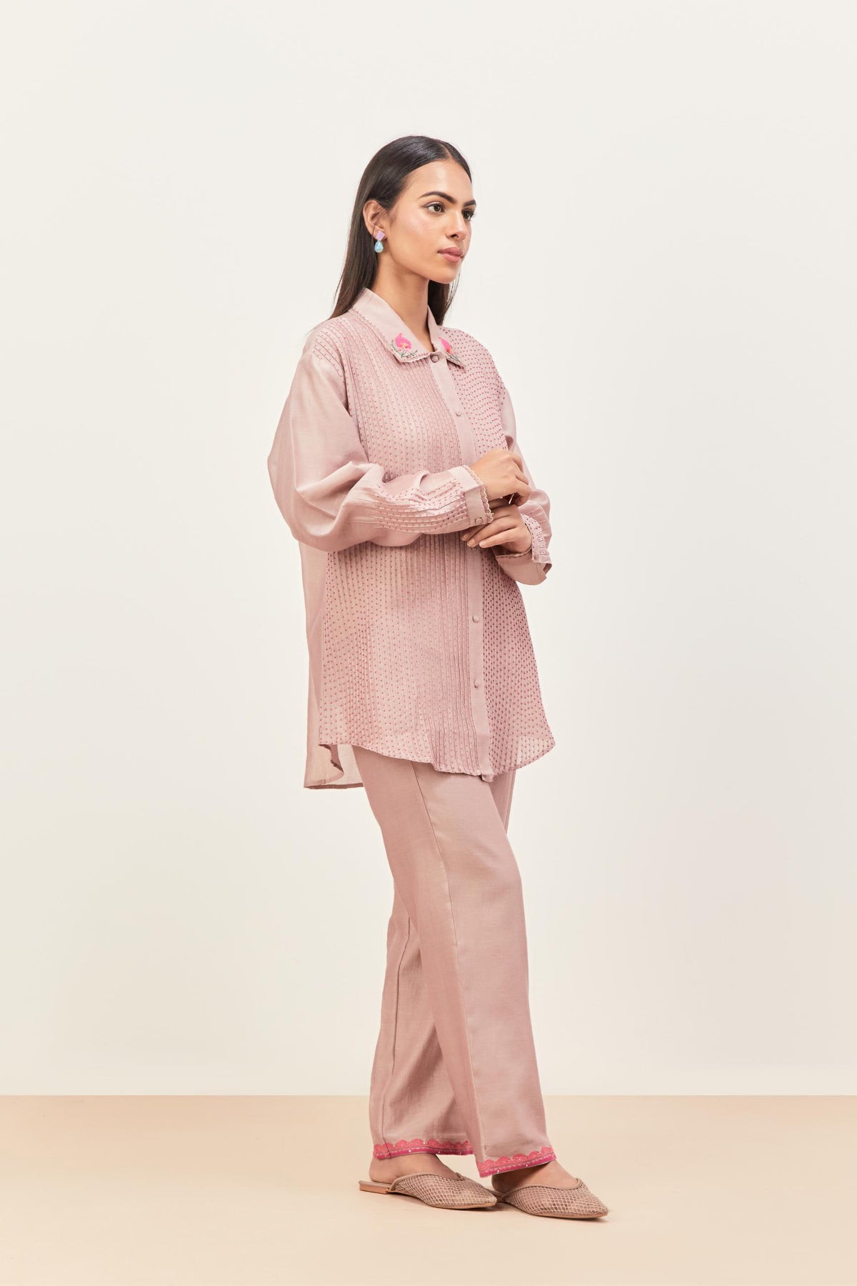 Lilac silk chanderi shirt with all-over pin tucks, highlighted with contrast beads in the front, paired with Lilac silk chanderi straight pants detailed with multi colored applique, highlighted with sequins work at bottom hem.