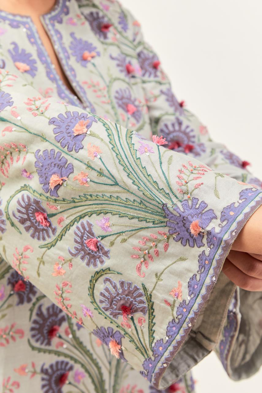Bluish Grey short A-line silk chanderi kurta set, fully embroidered with appliqué flowers, highlighted with aari thread work and silk tassels.