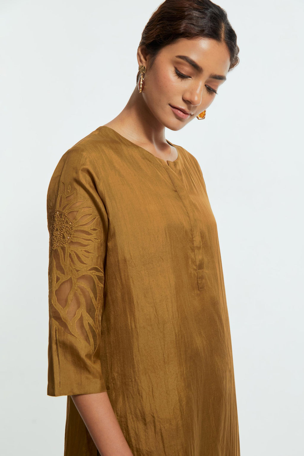 Olive silk straight kurta set adorned with appliqué chrysanthemum motifs along one side and both sleeves, delicately highlighted with fine French knots and subtle sequins.