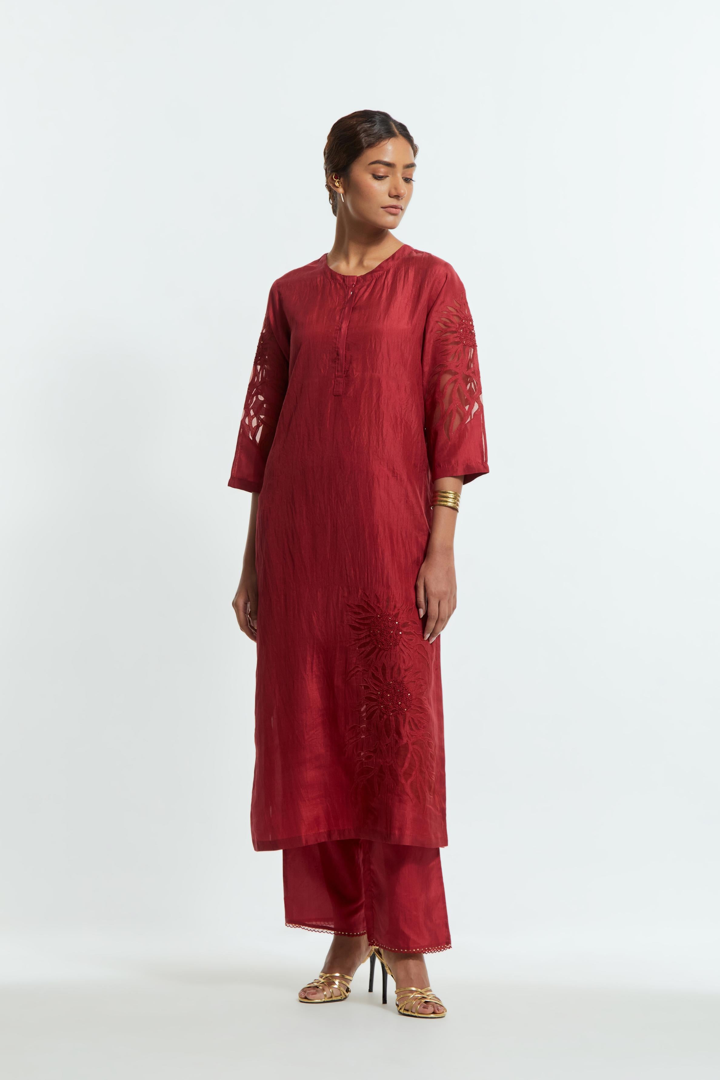Red silk straight kurta set adorned with appliqué chrysanthemum motifs along one side and both sleeves, delicately highlighted with fine French knots and subtle sequins.