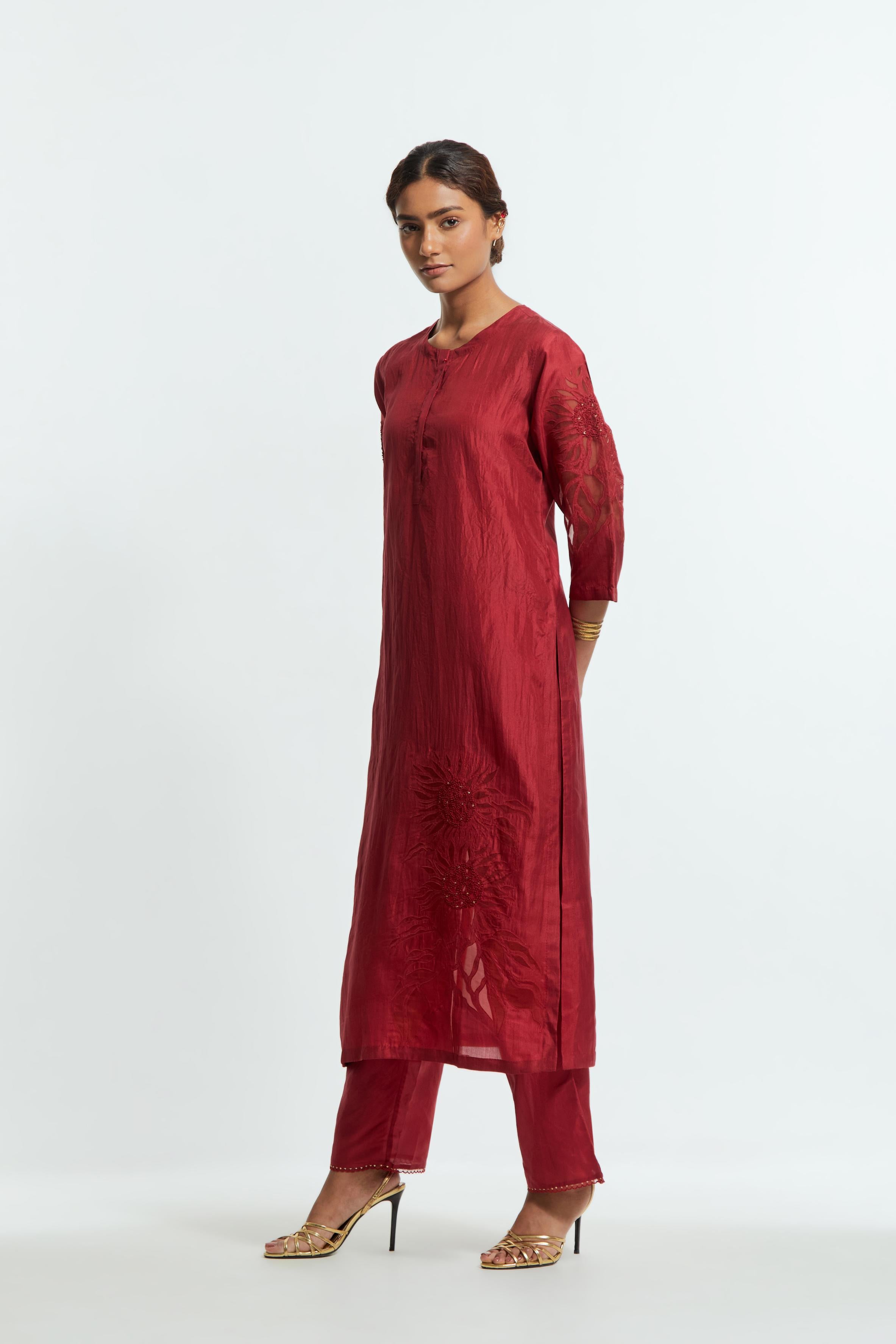 Red silk straight kurta set adorned with appliqué chrysanthemum motifs along one side and both sleeves, delicately highlighted with fine French knots and subtle sequins.