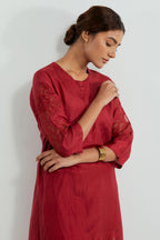Red silk straight kurta set adorned with appliqué chrysanthemum motifs along one side and both sleeves, delicately highlighted with fine French knots and subtle sequins.