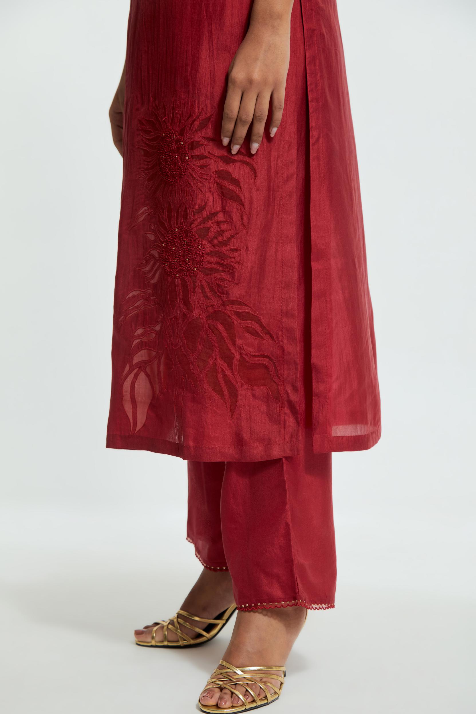 Red silk straight kurta set adorned with appliqué chrysanthemum motifs along one side and both sleeves, delicately highlighted with fine French knots and subtle sequins.