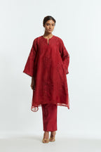 Red silk organza A-line short kurta adorned with delicately placed floral appliqué motifs and subtle sequin embellishments. Paired with red silk straight pants detailed with scalloped organza edging at the hem, highlighted with gold sequins work.