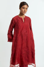 Red silk organza A-line short kurta adorned with delicately placed floral appliqué motifs and subtle sequin embellishments. Paired with red silk straight pants detailed with scalloped organza edging at the hem, highlighted with gold sequins work.
