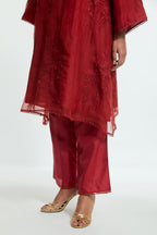 Red silk organza A-line short kurta adorned with delicately placed floral appliqué motifs and subtle sequin embellishments. Paired with red silk straight pants detailed with scalloped organza edging at the hem, highlighted with gold sequins work.